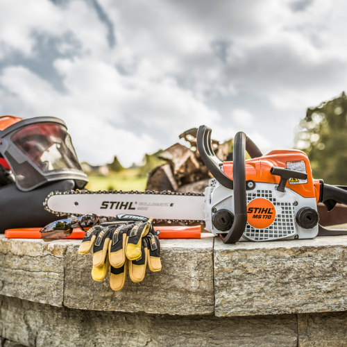 A Stihl chainsaw and gear posed on a rock ledge.