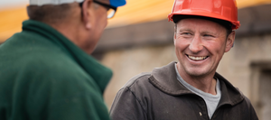 A close up of contractors in hardhats talking and smiling.
